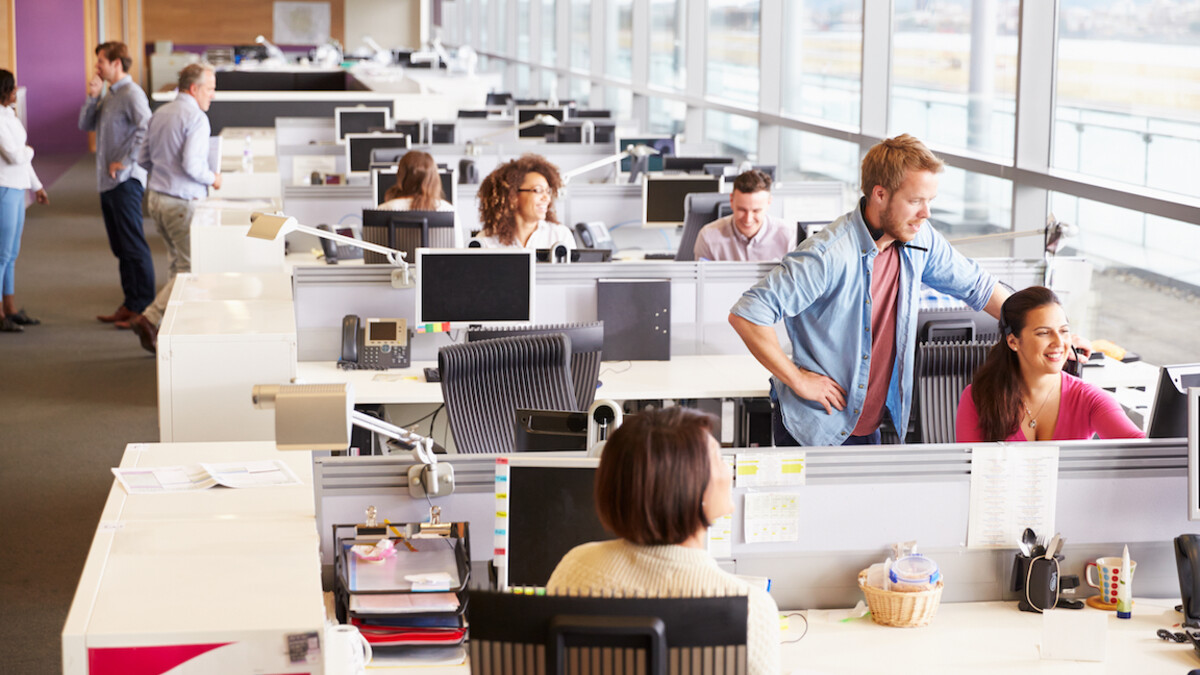 Casually dressed colleagues talking in an open plan office