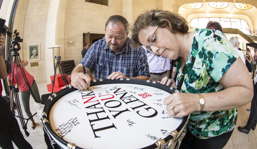 John Bailey and Gretchen Foley sign a bass drum during the Aug. 20 celebration of an $8 million gift by Glenn Korff. The drum was a gift for Korff. 