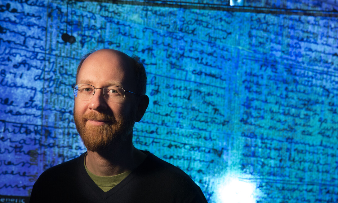 drian S. Wisnicki, assistant professor of English, stands in front of a projected image of Dr. David Livingstone's 1871 diaries made readable using spectral imaging technology.