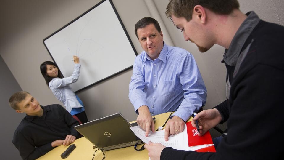  Eric Thompson (second from right), associate professor of economics, works with student research assistants in the College of Business Administration’s Bureau of Business Research. The bureau is designed to assist with Nebraska’s economic development efforts.