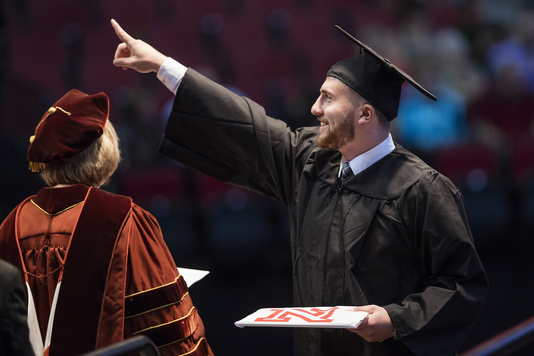 Murat Kuzu gestures to friends after receiving his business degree.