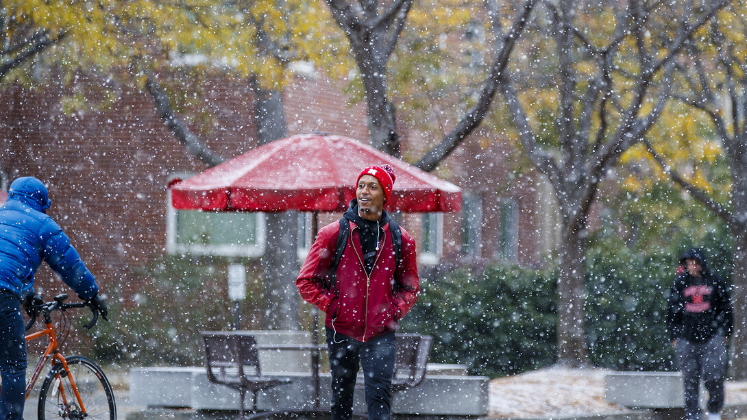 A student smiles as snow falls during his walk across City Campus on Oct. 30. 