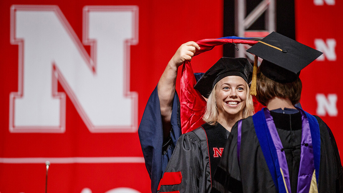 Amy Mantz smiles at her adviser, Angie Pannier, while receiving her doctoral hood.