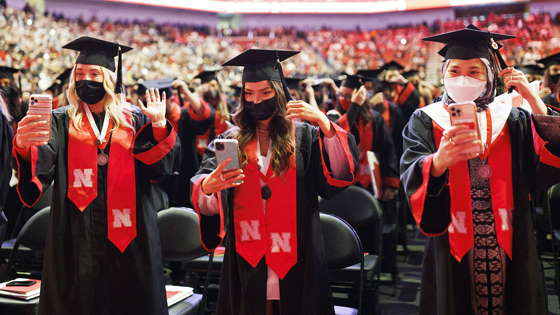 Chancellor’s Scholars Paxton Brittingham (left), Khiana Blizek (center) and Nur Azhani Nazifa Binti Azhar (right) record the turning of their tassels at the end of the undergraduate commencement ceremony Dec. 18 at Pinnacle Bank Arena.