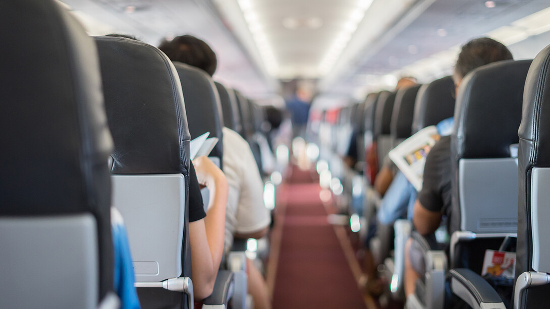 Aisle of an airplane from behind, with passengers reading