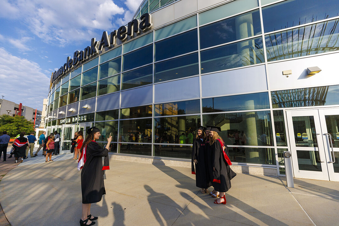 Three graduates pose for a picture outside Pinnacle Bank Arena after the ceremony.