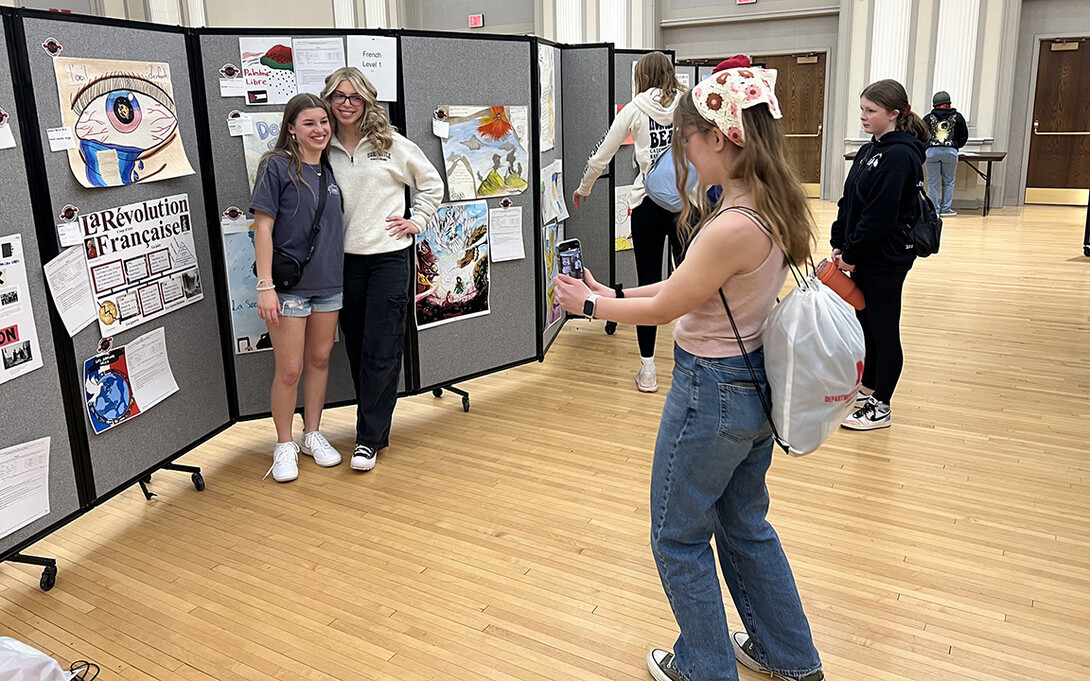 Students representing Lincoln East in the poster contest pose for a picture next to their entry.