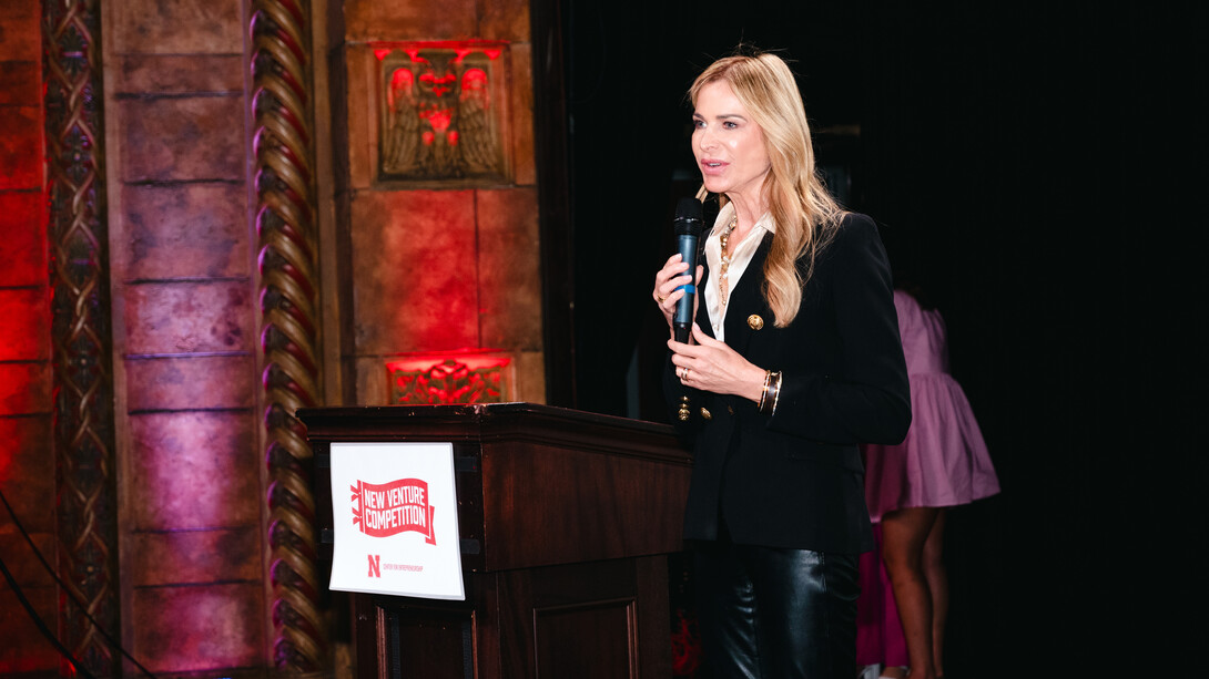 Janna Ronert holds a microphone behind a lectern. 