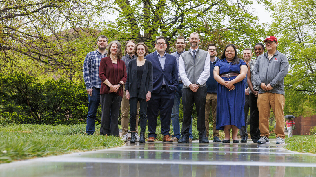 Twelve people stand on a sidewalk and lawn.