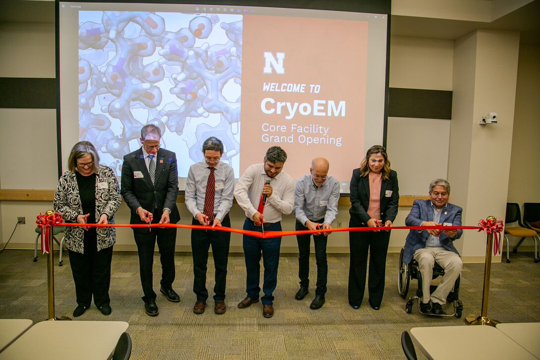 Five men and two women cut a ceremonial red ribbon.