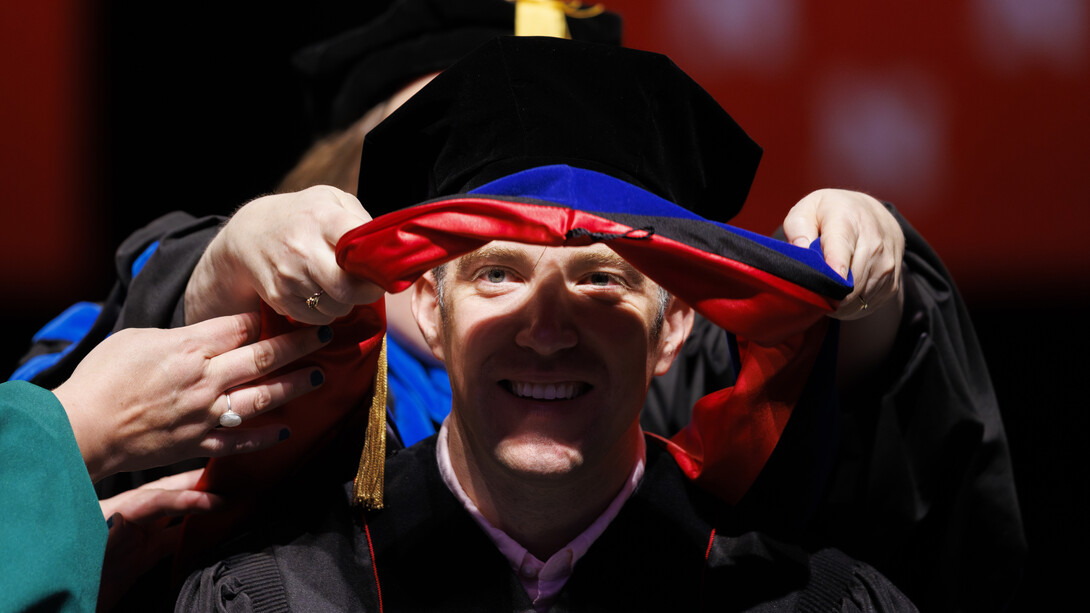 Alexander Farquhar-Leicester of Lincoln watches as his doctoral hood is lowered over his head.