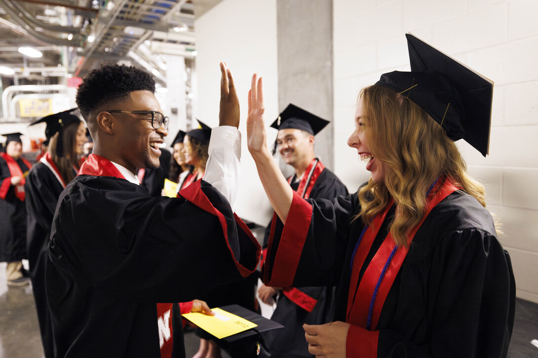 Brandon McMiller of Omaha and Natalie Bender of Lincoln high-five as they wait with other College of Journalism and Mass Communications undergraduates.