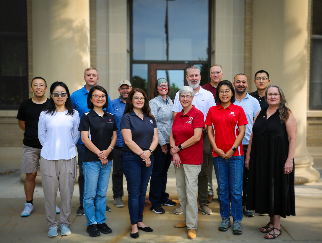 An outdoor group photo of 14 researchers