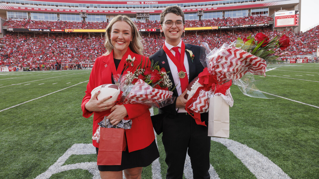 Husker seniors Emmerson Putnam (left) and Jamie Smith pose with footballs, flowers and gift bags on the 50 yard line of Memorial Stadium after being crowned homecoming royalty.