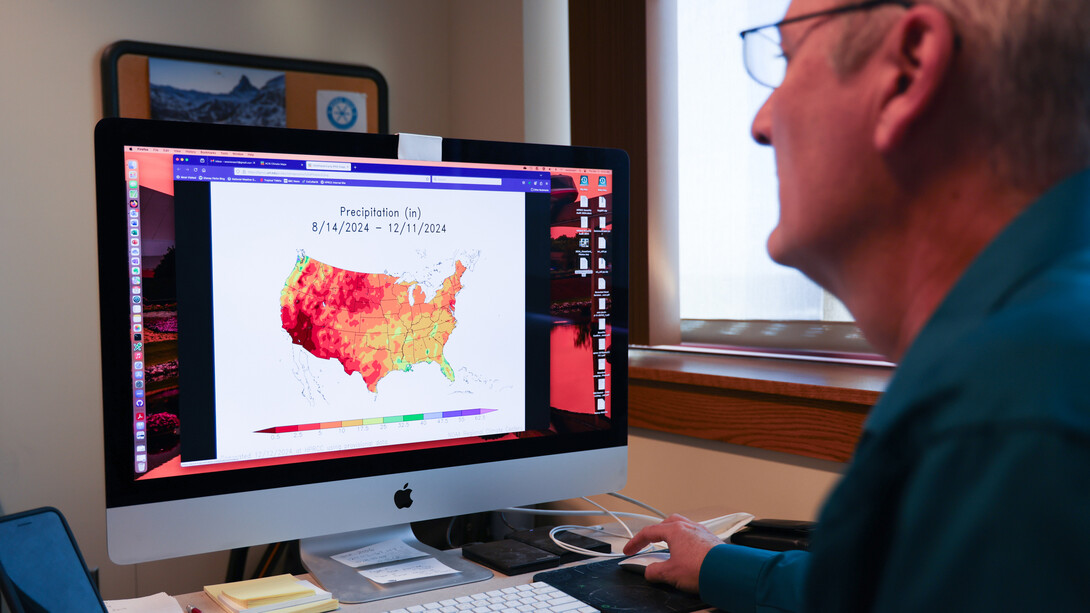 Bill Sorensen, senior applications/systems programmer for the High Plains Regional Climate Center, reviews an Applied Climate Information System map showing precipitation levels throughout the country during the last four months.