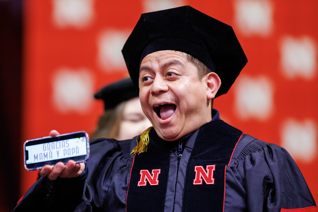 Héctor de Jesús Palala Martínez smiles as he displays the phrase “Gracias Mama y Papa” on his phone before receiving his doctoral hood.