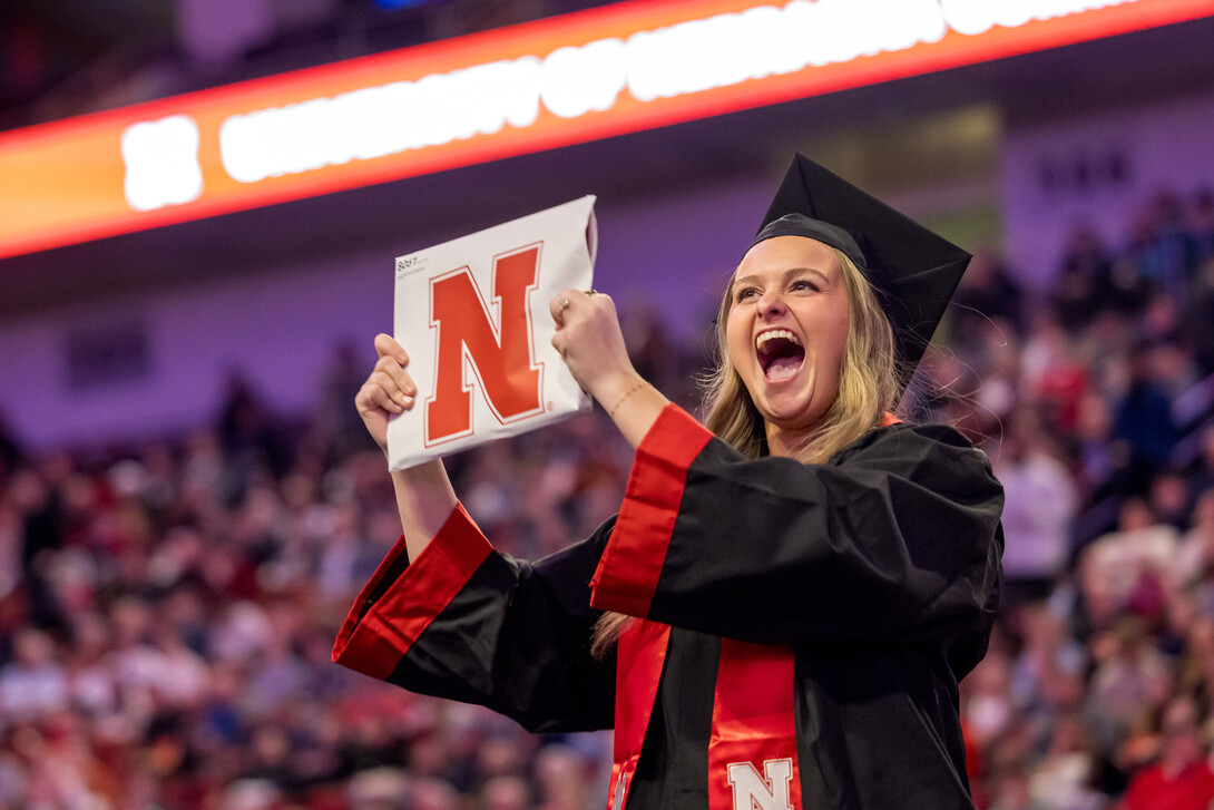 Emily Nordby, dressed in graduation regalia, shows off her newly earned Bachler of Science in Education and Human Sciences during the undergraduate commencement ceremony Dec. 20 at Pinnacle Bank Arena.
