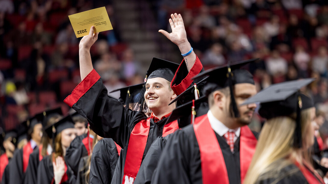 Andrew Johnson of Lakewood Ranch, Florida, waves to people in the crowd as he takes his seat for the undergraduate commencement ceremony Dec. 20 at Pinnacle Bank Arena.