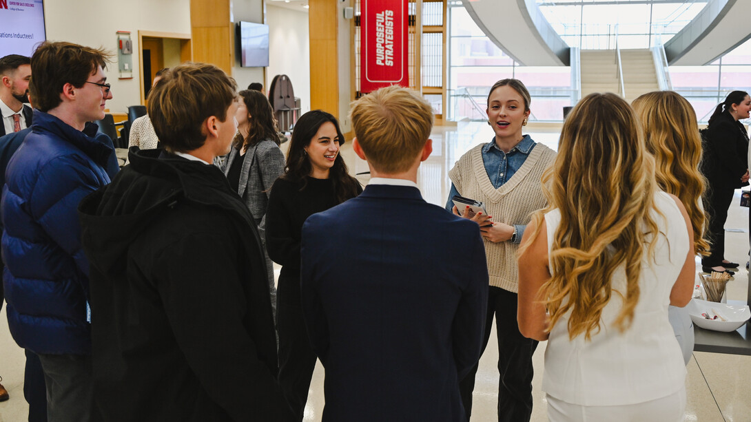 A young woman speaks to a group of University of Nebraska–Lincoln students in the atrium of Howard L. Hawks Hall.