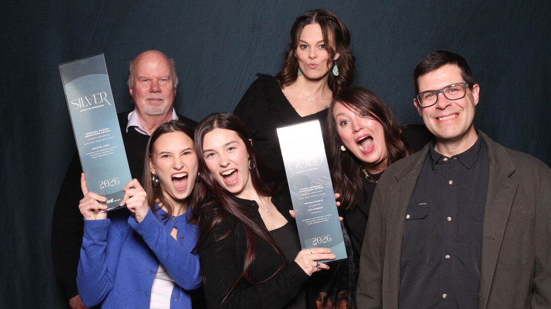 Four women and two men pose with two awards.