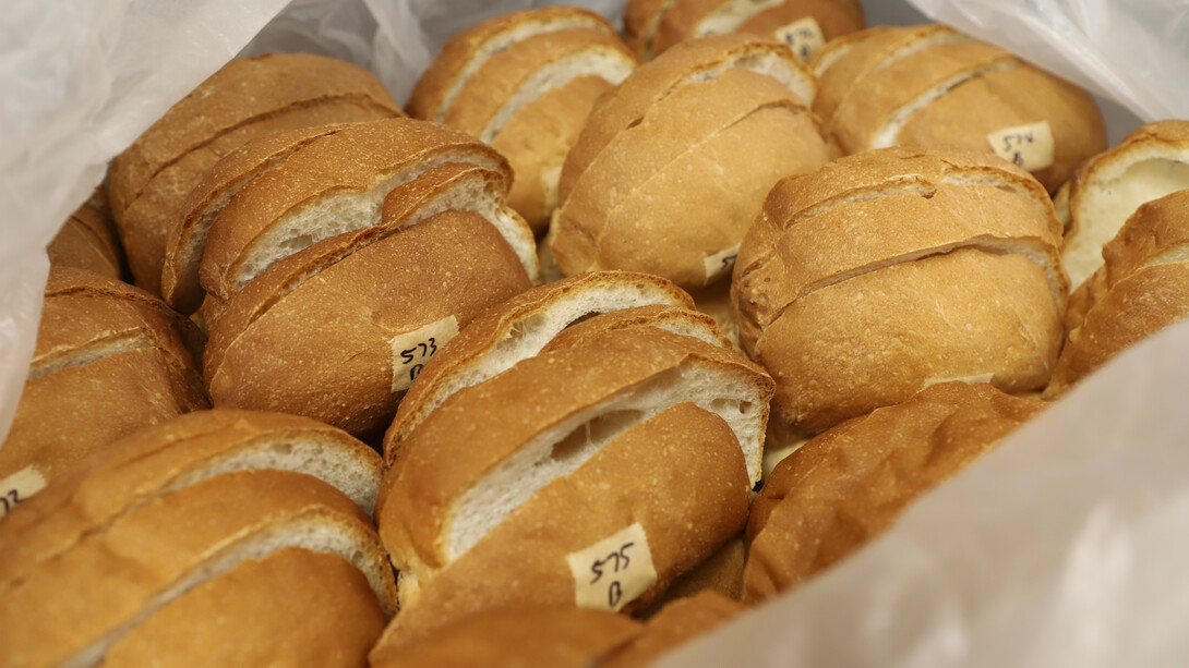 A close-up of a dozen or so small loaves of bread, with labels on them.
