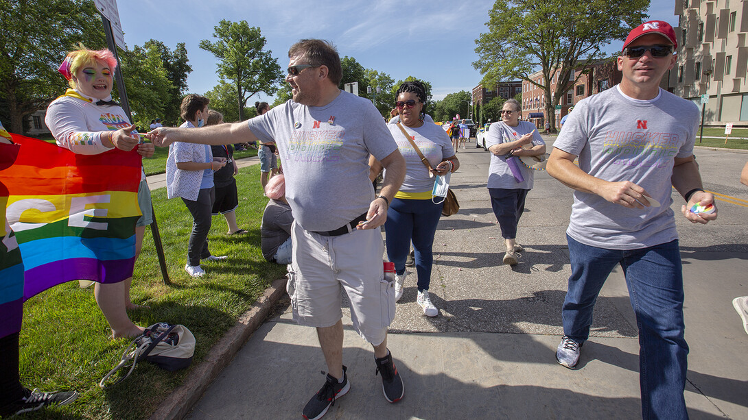 Corrie Svehla hands out a Husker Pride sticker during the Star City Pride parade on June 19.