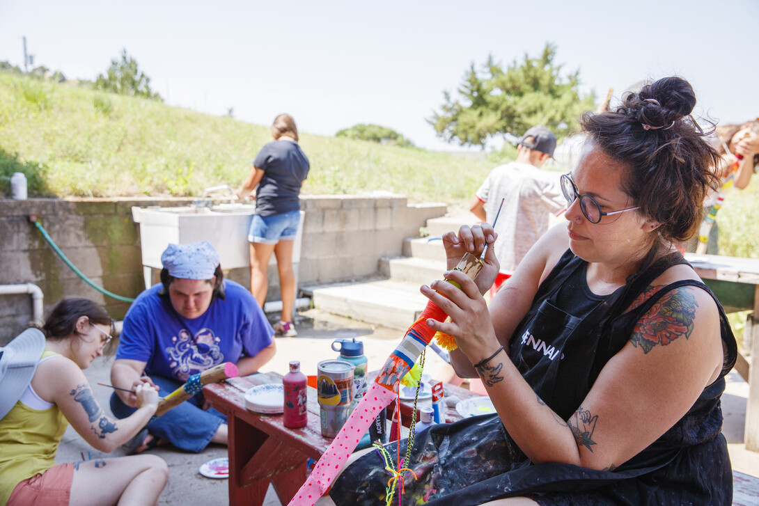 A counselor and students work on artful walking sticks.