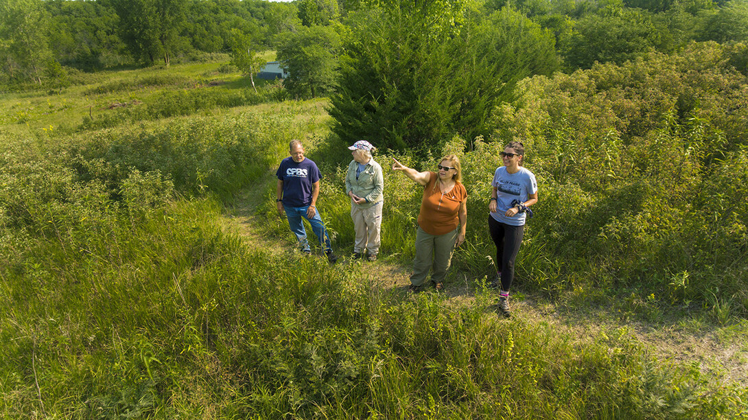William Belcher, associate professor of anthropology (left); LuAnn Wandsnider, professor of anthropology; Sophia Perdikaris, director of the School of Global Integrative Studies; and Kat Krutak-Bickert, unit coordinator for SGIS, look over the Reller Prairie Field Station.