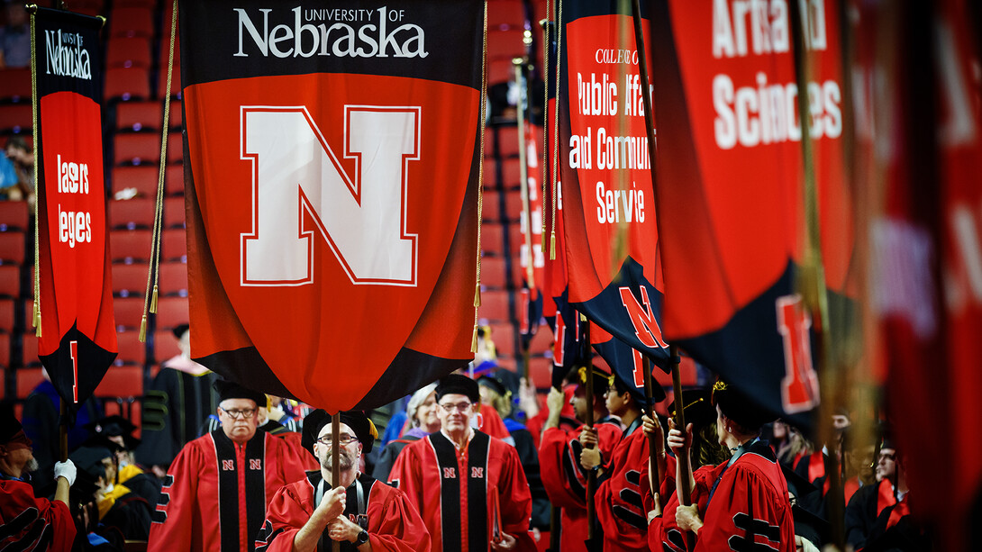 Members of the University Marshal Corps carry gonfalons into Pinnacle Bank Arena at the start of the summer 2022 commencement on Aug. 13.