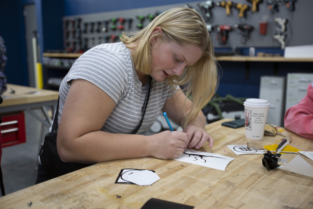A Bay High student cuts out a vinyl sticker using an Xacto knife.