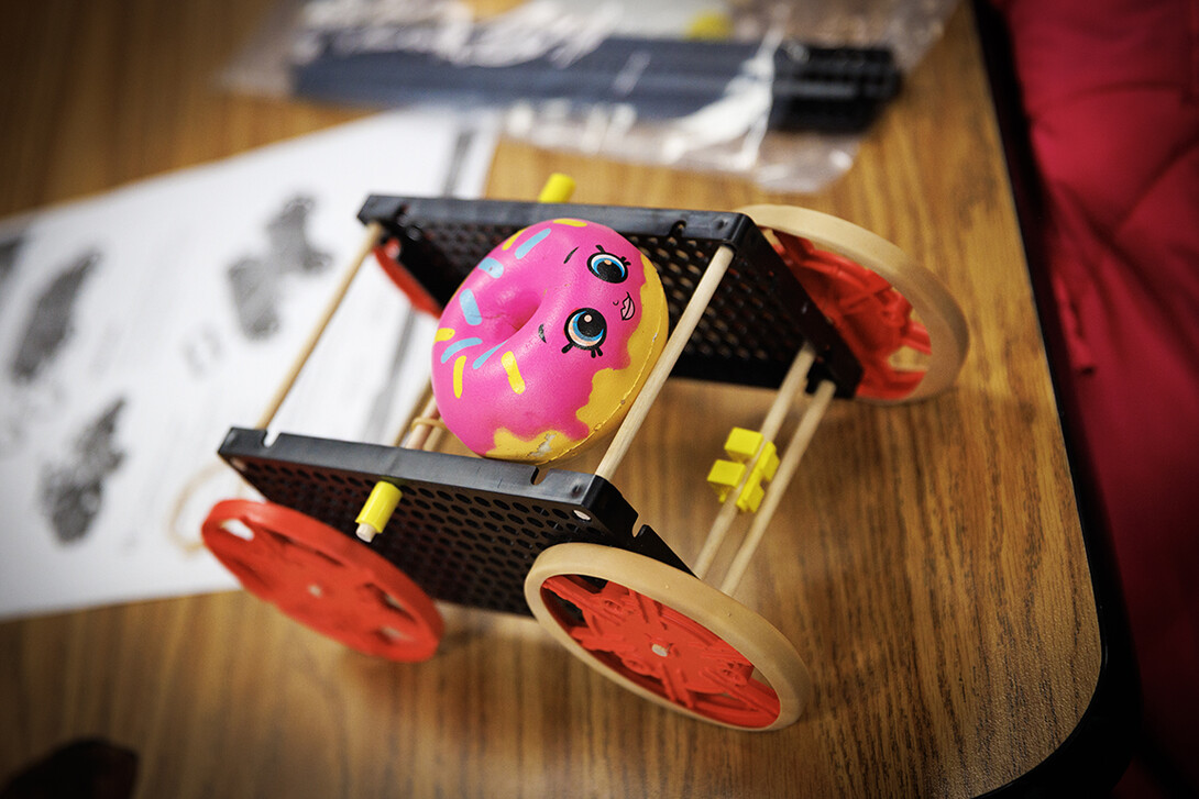 A doughnut squishy decorates a rubber-band powered car.