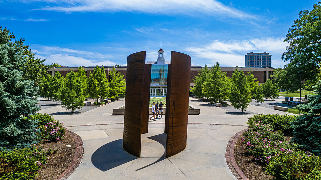 Blue summer skies, trees and sculpture frame the Love Library cupola