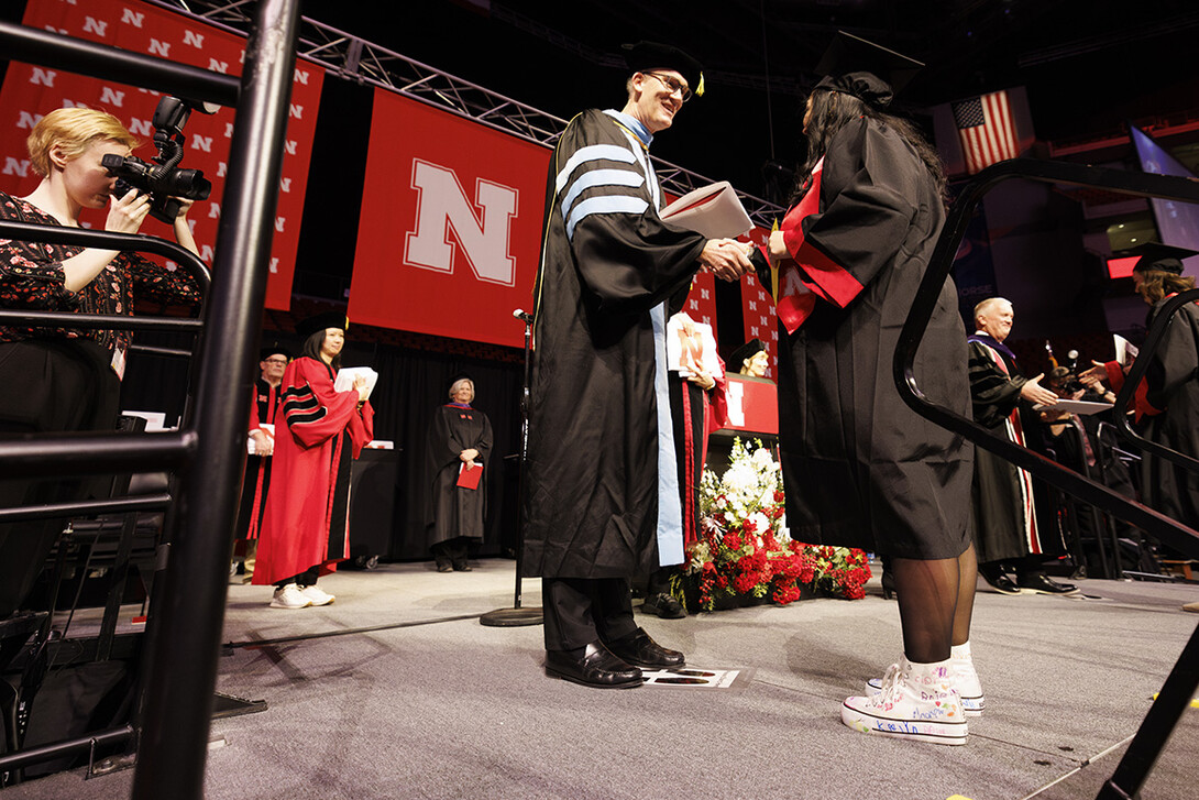 Crandall Blake receives her diploma from acting dean Nicholas J. Pace. Blake is wearing high tops she had her kindergarten students she student taught sign so they could walk on stage with her.