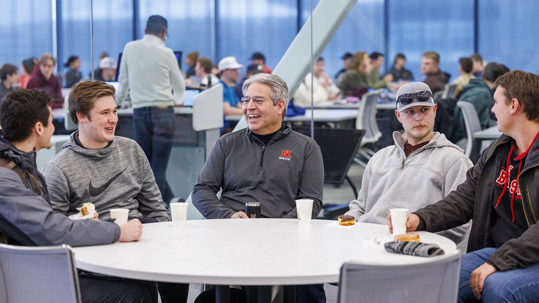 Dean Lance C. Pérez talks with four male students at a table.