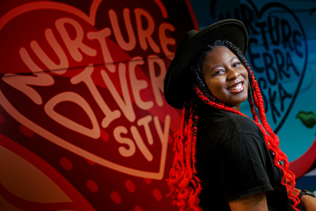 Alana Ross smiles for a photo in front of a mural in Anderson Hall.