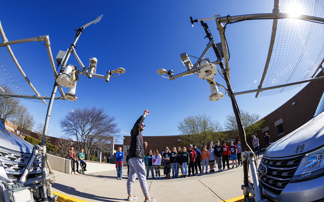 Ben Schweigert, a graduate student in geosciences, explains the instruments hanging off the front of the TORUS storm chasing vehicles. The instrument supports also include fencing to ward off hail stones from breaking the windshields.  Graduate students in Adam Houston’s TORUS weather chasing team spoke to students at Millard School District’s Russell Middle School in Omaha.