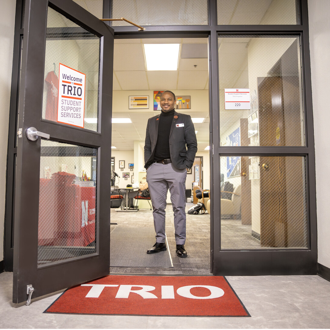 Cameron Woodard, Director of TRIO Programs at UNL, poses at the doors of the TRIO offices.