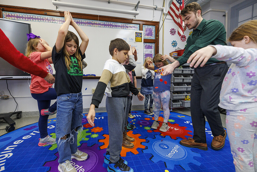While students close their eyes and pretend they are trees, Jack Hilgert, drops red, yellow and blue chips on the floor. The chips represent nutrients, sunshine and water. The students then open their eyes and scramble to pick up a balance of chips to help their “trees” grow.