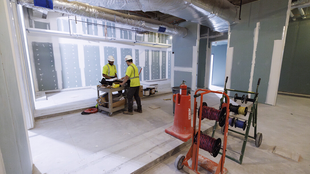 Workers looking over plans in what will be a Campus Rec Center locker room.