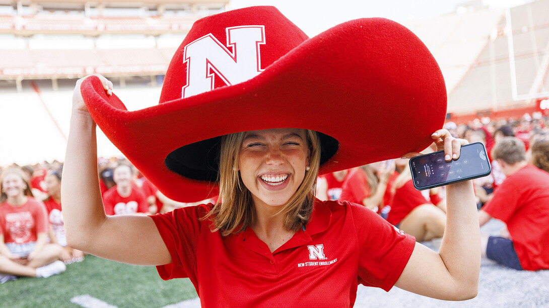 Claire Kelly, a New Student Enrollment leader, tries on Herbie’s hat after the Class of 2027 "N" photo in Memorial Stadium on Aug. 23.