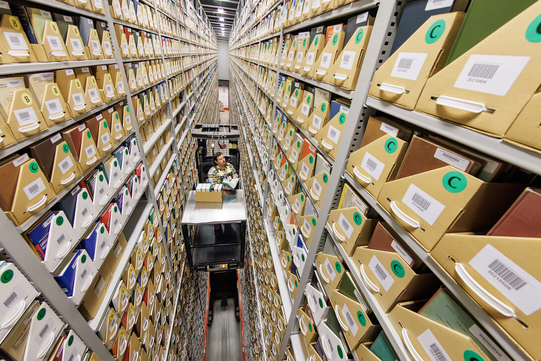 Several stories above the ground, Josh Caster, Archives Manager for University Libraries, retrieves a book stored in the Library Depository Retrieval Facility on East Campus.
