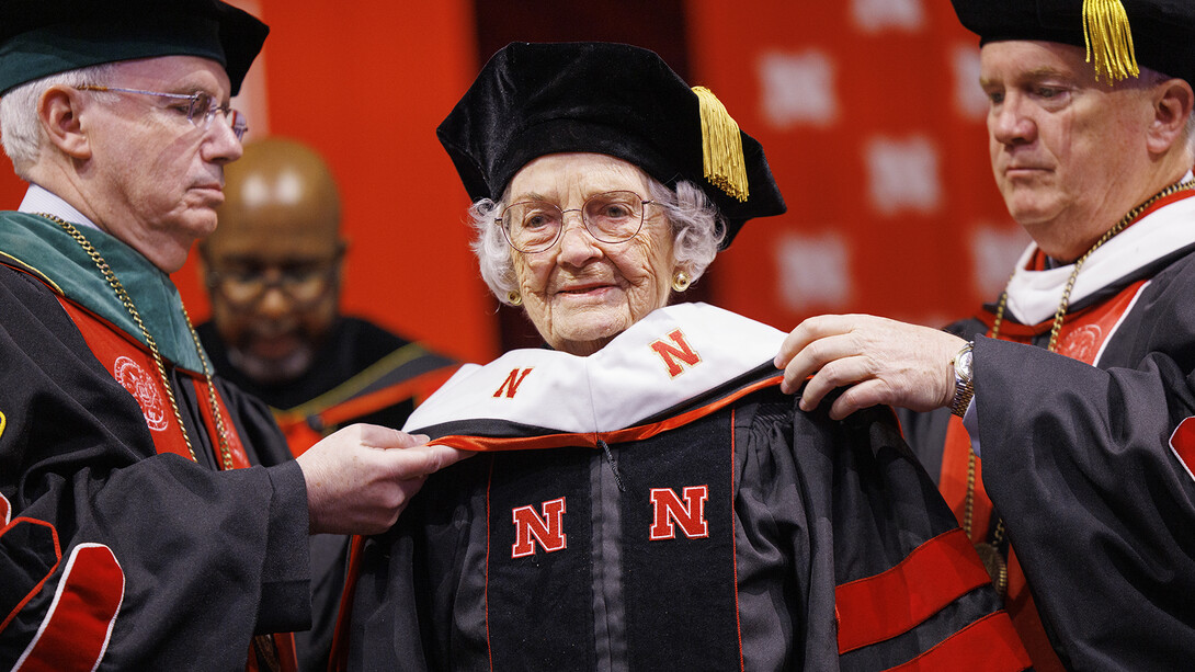 Marion (Patton) Larmon receives her honorary Doctor of Fine Arts hood from (left) Dr. Jeffery Gold, president of the University of Nebraska, and Regent Tim Clare, regent.