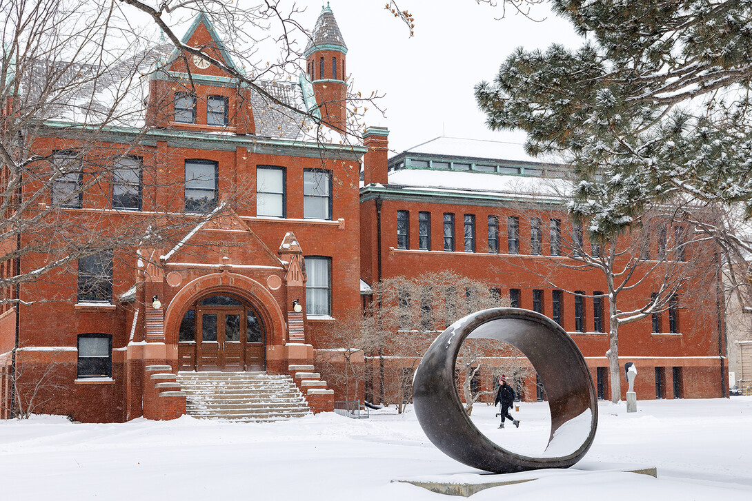 A student walks past Architecture Hall as snow falls on the morning of Feb. 12. The winter storm closed campus for the day, and classes and work shifted to remote formats.