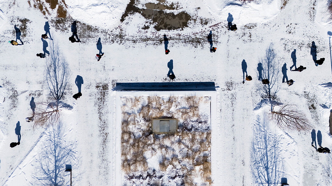 Student’s shadows are cast onto the snow as they walk past the Adele Learning Commons. February 19, 2025. 