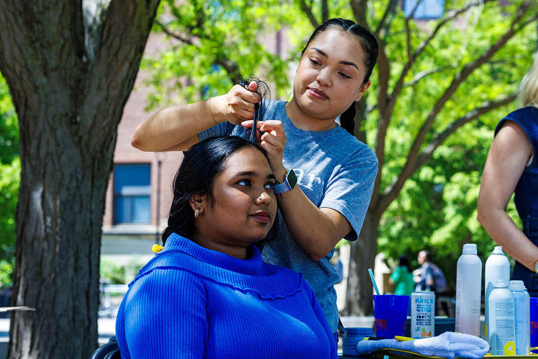 Bhavana Sreekumar, a Community & Regional Planning Graduate Student, getting her hair braided by an employee from DryBar at the “FriYay Unwind Fest” on City Campus. 