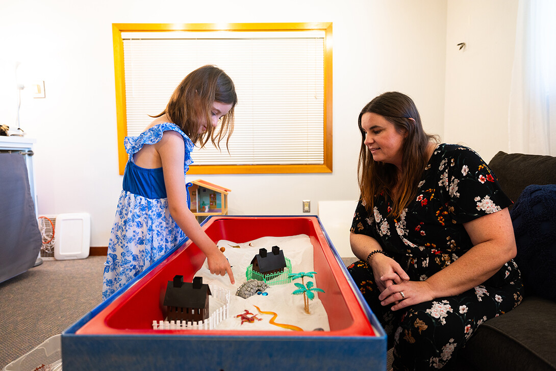 Jamie Buhrman, a first-year graduate student in Child, Youth and Family Studies, watches her daughter, Stella, play in a sand table in the family therapy and play room in the Couple and Family Clinic on East Campus.