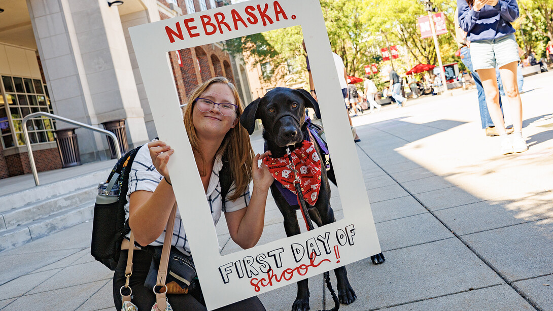 Student posing for a first-day photo with her service dog.