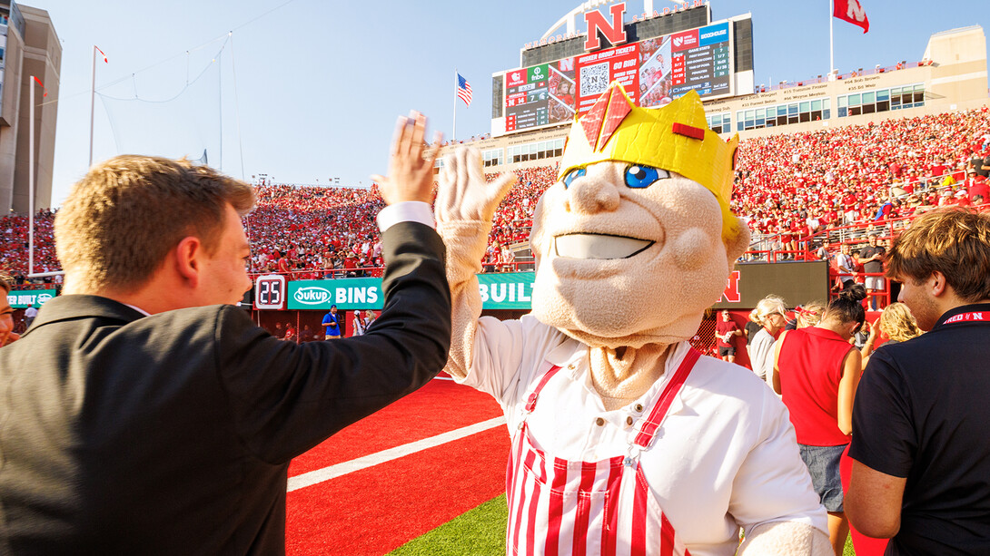 Homecoming King, Caden Connelly high fives Herbie, who's wearing a crown to celebrate the 2025 Homecoming winners.