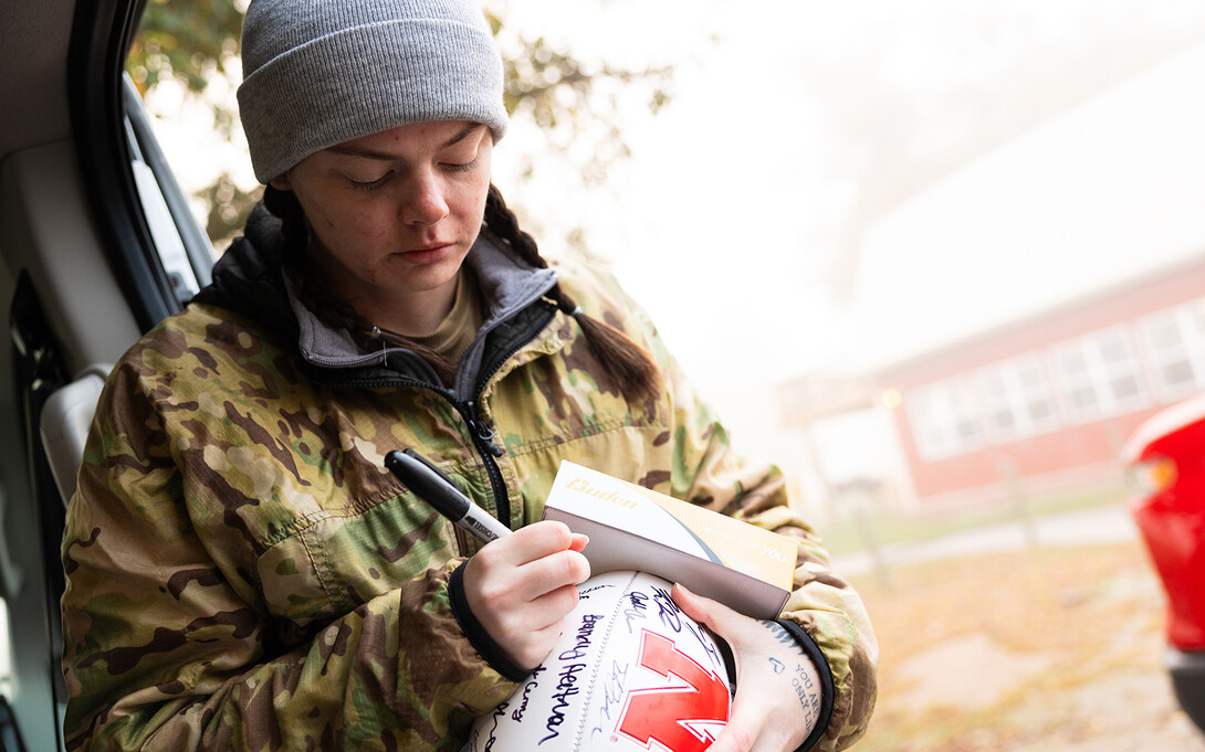 Emily Dietzman, a psychology major and six-year veteran of the Air Force, adds her signature to a football covered with the names of civilian supporters, ROTC students, student veterans and military veterans who joined the 2025 Ruck March.