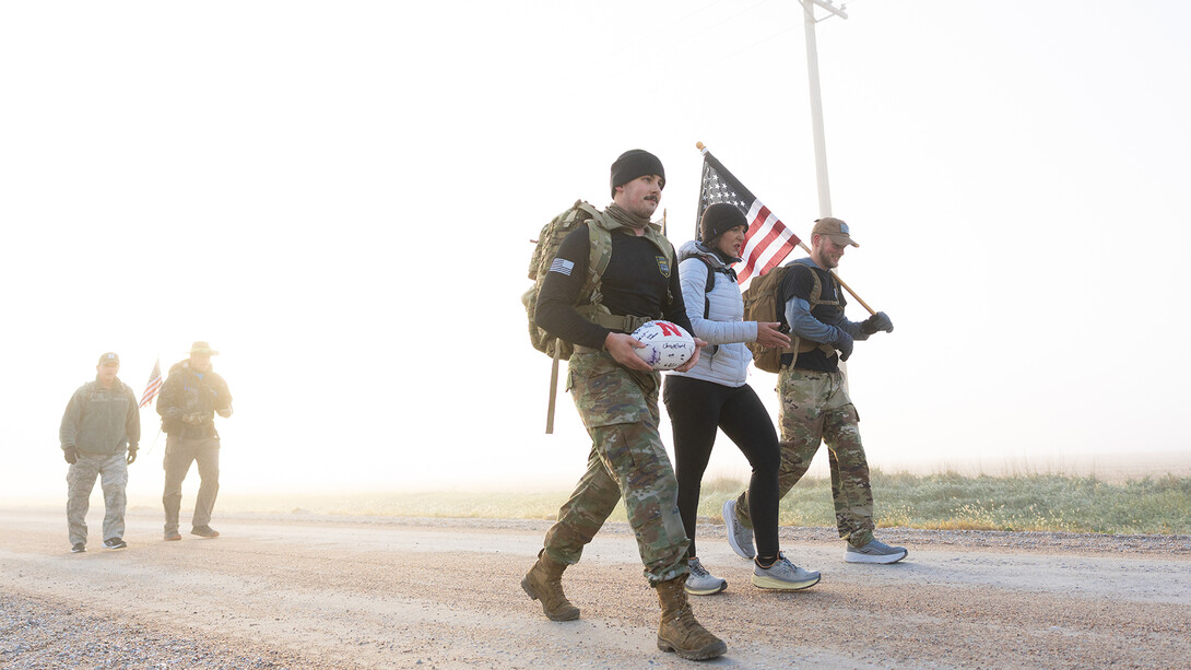 Five participants walk along Fletcher Avenue between Murdock and Alvo during the Oct. 30 morning leg of the annual ruck march, with a support vehicle following behind. The multi-day march begins in Omaha and ends at Memorial Stadium to raise awareness of veteran suicide and encourage seeking mental health support.